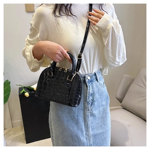 Detail of black crocodile texture shell bag with gold hardware and top handles