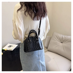 Close-up of black crocodile embossed texture on a retro shell-shaped crossbody bag