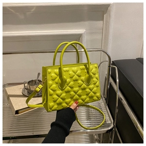 Close-up of bright green handbag featuring 3D embossed clover textures and sturdy handles