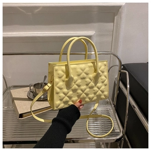 Detail of yellow embossed clover pattern on a structured vegan leather handbag with top handles
