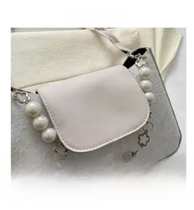 Detail of embossed floral texture and pearl strap on the cream fashion handbag
