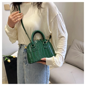 Detail view of mini green crocodile pattern shell bag with golden hardware and dual zippers