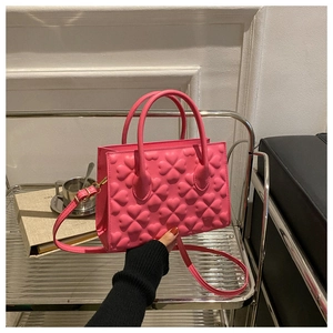 Close-up of rose pink handbag featuring 3D heart embossing and round handles