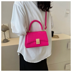 Detail of rose red crocodile embossed handbag featuring woven handle and gold twist lock