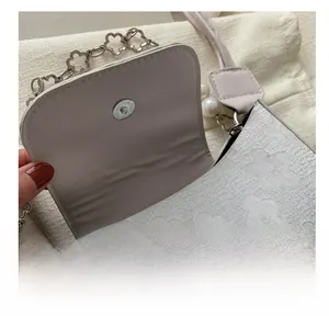 Detail of magnetic snap closure on vintage embossed floral shoulder bag with pearl charms