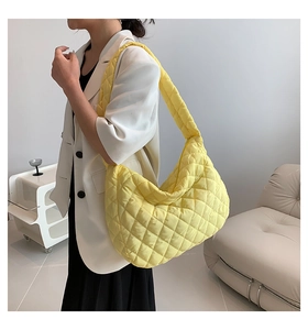 Detailed view of yellow quilted puffer tote bag with wide shoulder strap on model