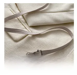 Detail of off-white leather shoulder strap with silver metal swivel hook and buckle