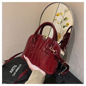 Close-up of burgundy crocodile pattern shell bag with golden zipper and dual handles
