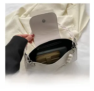 Detailed interior of a white crossbody bag with pearl chain showing large phone and wallet