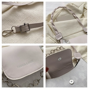 Detailed view of cream handbag with floral embossing, braided handle and pearl chain