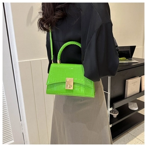 Detail of neon green crocodile pattern bag with golden buckle and woven handle