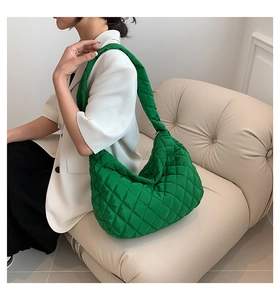 Detail of green quilted puffer hobo bag with large capacity and shiny finish texture