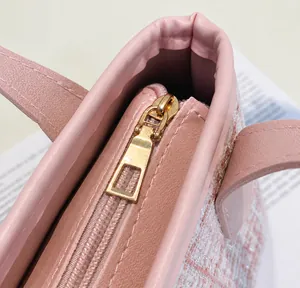 Dettaglio della cerniera dorata e del tessuto in tweed rosa della borsa a secchiello