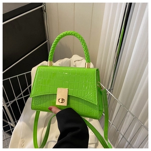 Detail of neon green crocodile texture handbag with gold clasp and woven handle