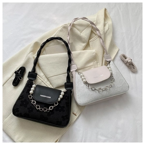 Detail view of floral jacquard bag with pearl chain and braided strap on beige blazer