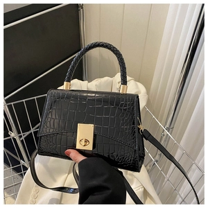 Detail of black faux crocodile handbag with woven handle and gold twist lock closure