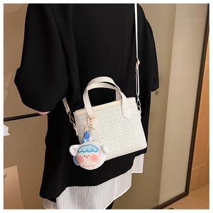 Dettaglio borsa tote intrecciata bianco sporco con ciondolo in peluche e tracolla