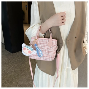 Borsa a secchiello in tweed rosa con ciondolo di peluche e tracolla in pelle indossata