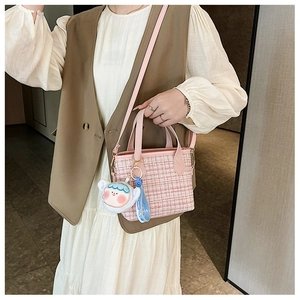 Dettagli della borsa a secchiello in tweed rosa con ciondolo a cartone e trama tessuta