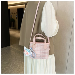 Borsa a secchiello in tweed rosa con ciondolo di peluche vista laterale su una modella