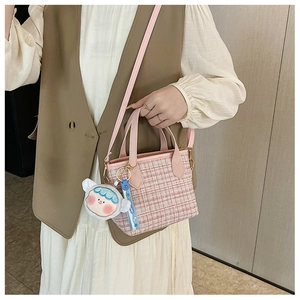 Dettaglio della borsa a secchiello in tweed a quadri rosa con ciondolo e tracolla