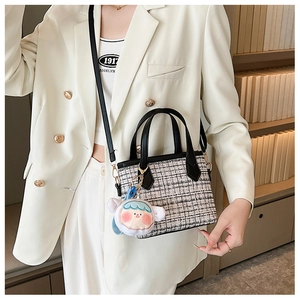Dettaglio borsa a secchiello in tweed con ciondolo peluche e tracolla su blazer bianco