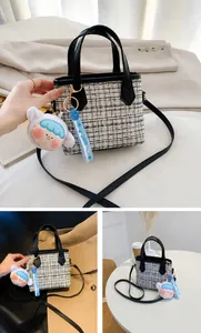Dettaglio borsa a secchiello in tweed bianco e nero con tracolla e ciondolo