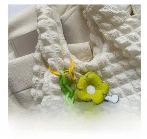 Detail of yellow-green flower charm with beaded chain on white bubble texture tote bag