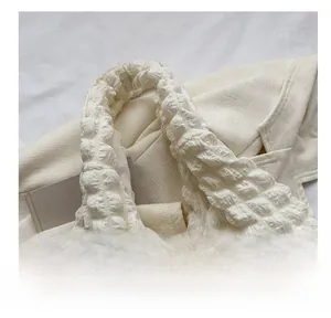 Detail view of white bubble texture tote bag with yellow flower charm and green chain
