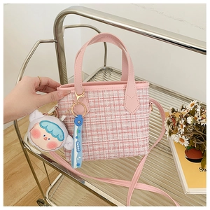 Dettaglio della borsa a secchiello in tweed rosa e bianco con ciondolo a forma di ragazzo