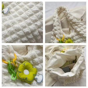 Detail of white popcorn textured tote bag showing spacious interior and floral charms