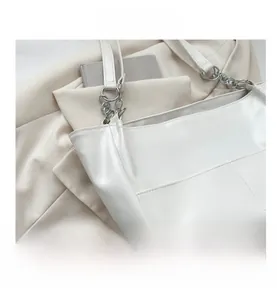 Close-up of white leather tote bag featuring horizontal stitching and silver chain strap