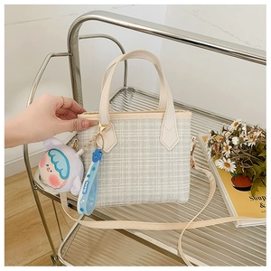 Dettaglio di una mini borsa a secchiello beige a quadretti con ciondolo in peluche