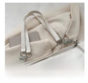 Close-up of white leather tote handle with silver metal chain link and ring hardware