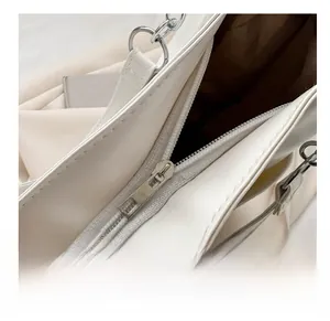 Detail view of the smooth silver zipper and dark lining on white faux leather tote bag
