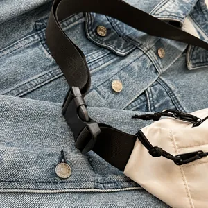 Gros plan sur la boucle noire et la sangle en nylon d'un sac à bandoulière blanc