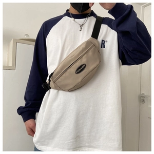 Detailed view of beige nylon waist bag with adjustable black strap and fashion patch
