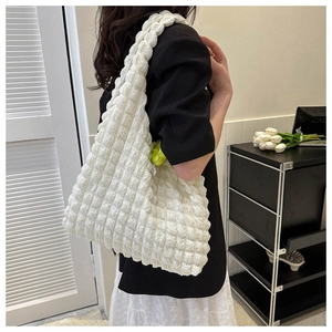 Detailed view of white bubble texture tote bag worn by a model in a minimalist setting