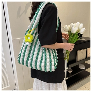 Detail of green and white striped tote bag featuring bubbly texture and flower charm