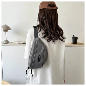 Close-up of gray nylon crossbody bag featuring double zippers and Fashion label detail