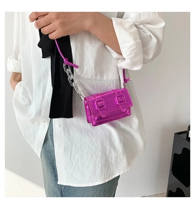 Detail of mini magenta patent leather crossbody bag with metallic chain strap