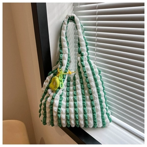 Detail of green and white striped popcorn texture tote bag with yellow flower charm