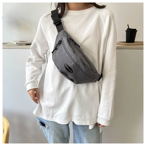 Gray nylon crossbody chest bag with adjustable strap and fashion label on model