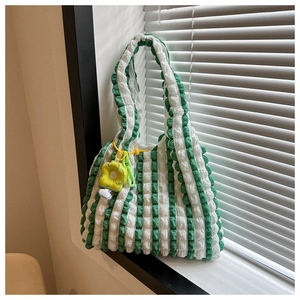 Close-up of popcorn texture tote bag with green striped pattern and yellow flower charm