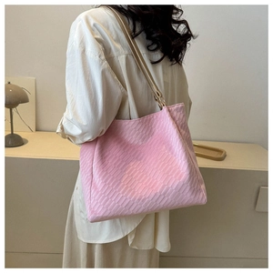 Close-up of pink woven texture tote bag worn by a model in a natural home setting