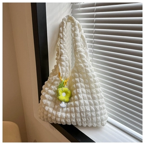 Detail of white bubble texture tote bag with green flower charm in natural window light