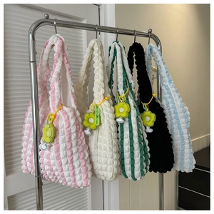 Detail of colorful popcorn texture tote bags with flower charms on a metal rack