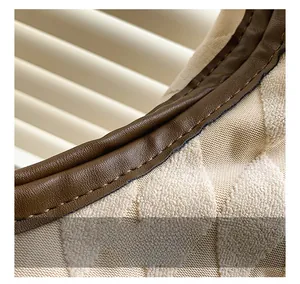 Detailed close-up of brown leather piping and beige quilted knit fabric with neat stitching