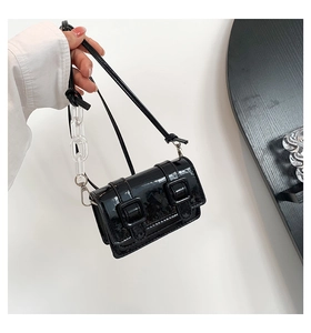 Close-up of black patent leather mini crossbody bag with a trendy acrylic chain strap