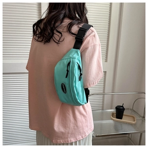 Close-up of mint green nylon crossbody bag with black adjustable strap and fashion label